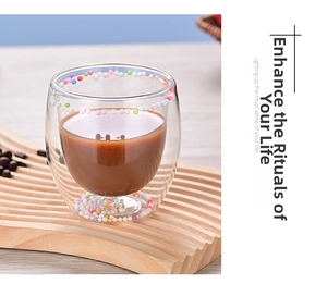 Detail shot of a double-walled glass cup with colorful beads on a wooden tray