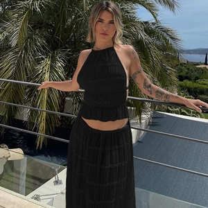 Dettaglio del set top a fascia nero e gonna lunga a pieghe con tessuto dalla texture operata