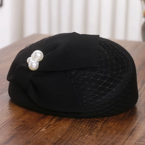 Detail of elegant black felt pillbox hat with bow, mesh veil and white pearls