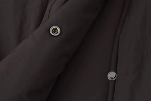 Detailed close-up of metal snap buttons and fabric texture on a brown cotton jacket