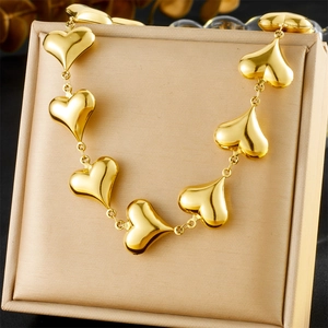Detailed view of a gold heart link chain necklace displayed on a beige jewelry gift box