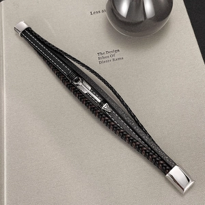 Close-up of multilayer braided leather bracelet with silver arrow charm on a book