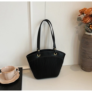 Detail of black tote bag featuring vertical pleated texture and gold metal ring hardware