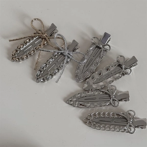 Silver metal bow hair clips set with rhinestone accents and chain designs on white surface