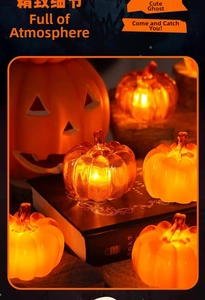 Close-up of translucent orange pumpkin LED lights with warm yellow glow on a dark desk