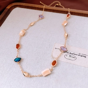 Detail of vintage gold necklace with colorful geometric gems and cream shell inserts
