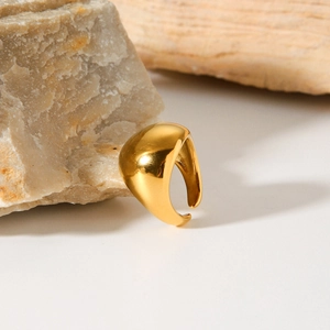 Detailed view of chunky dome gold plated stainless steel ring on natural stone background