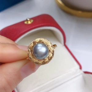 Close-up of a blue-grey freshwater pearl set on a woven golden ring band