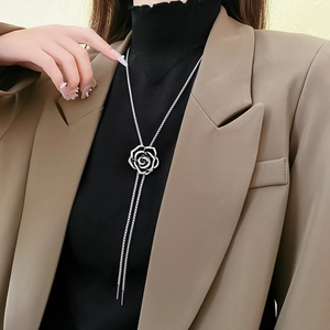 Detailed macro view of black camellia rose long necklace with silver hollow petals