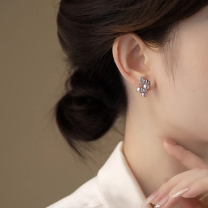 Close-up of elegant flower leaf earrings with purple pearls on model ear