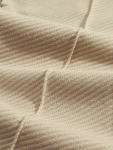 Detailed close-up of high-quality beige ribbed knit fabric texture on a casual jacket