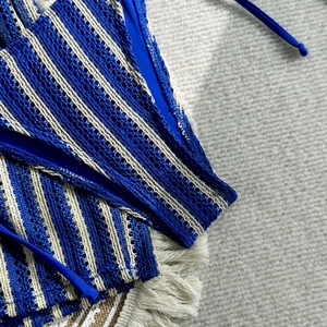 Detailed close-up of blue and beige striped crochet bikini fabric with tie-up strings