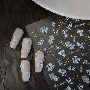 3D blossom nail stickers with white flowers and gold embroidery details on a black background