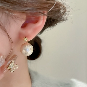 Vue détaillée de boucles d'oreilles perles goutte avec clous dorés et fini texturé