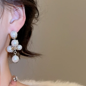 Primo piano di orecchini pendenti con perle francesi ed elegante design a goccia su modella