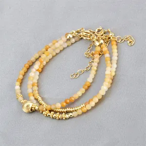 Close-up of yellow beaded bracelets set with gold lobster clasp and heart pendant details