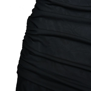 Détail du tissu en maille froncée noire d'une robe sexy à épaules dénudées et extensible