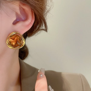 Close-up of amber resin geometric earrings with gold trim on a female model