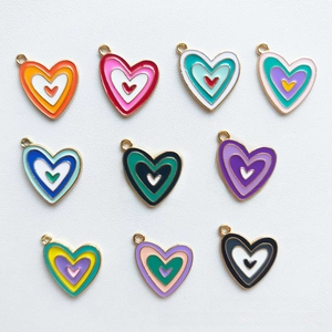 Flat lay macro of ten colorful enamel heart charms in gold alloy for DIY jewelry making