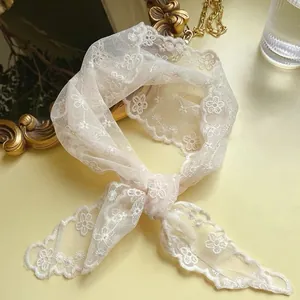Close-up of white floral embroidery on premium lace triangle bandana with mesh texture