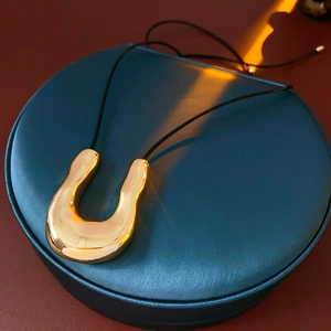 Gros plan d'un collier pendentif en U doré sur un coffret à bijoux en cuir bleu premium