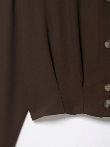 Detail view of brown shirt fabric with tortoiseshell button and single-breasted closure