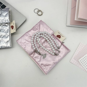 Rosa gesteppte PU-Tasche mit Schmetterlingsmuster und Perlenketten auf weißem Schreibtisch