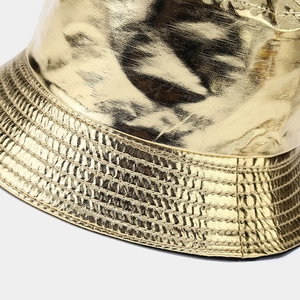 Dettaglio del cappello alla pescatora in pelle dorata con cuciture e trama metallica