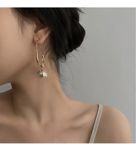 Nahaufnahme eleganter goldener Tropfenohrringe mit Perle am Ohrläppchen eines Models