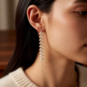 Close-up of elegant gold leaf-shaped tassel earrings with zircon crystals on a model