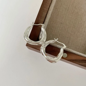 Minimalist 925 sterling silver irregular wave earrings on a wooden jewelry tray
