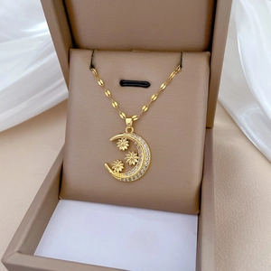 Elegant gold crescent moon and flower necklace with cubic zirconia in a jewelry box