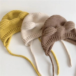 Detailed knit texture of baby earflap hats with bear ears in yellow, beige and brown colors