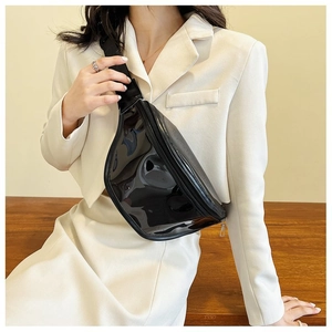 Detail of high-gloss black PVC chest bag featuring silver metal zipper and nylon strap