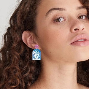 Acrylic cowgirl earrings featuring blue boots and white Let's Go Girls text on model