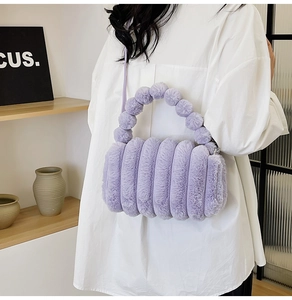 Close-up of purple plush tote bag with striped texture and furry ball handle detail