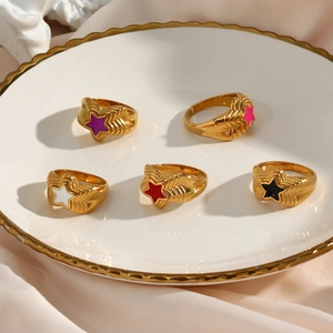 Detail of five stackable 18K gold-plated star rings in purple, pink, white, red, and black