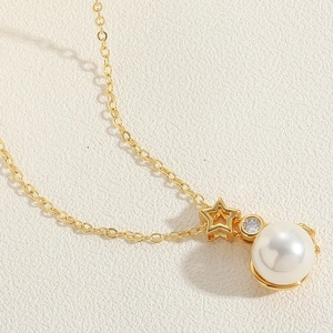 Detailed macro shot of a gold necklace featuring star, zircon, and large pearl pendant