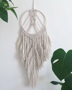 Detail of bohemian cream cotton macrame wall hanging with hand-woven feather leaves