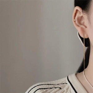 Detail of long gold snake chain tassel earrings with star stud worn by a model
