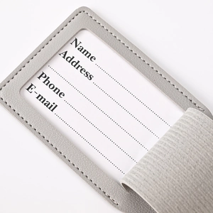 Macro view of grey PU leather luggage tag with clear window and adjustable strap