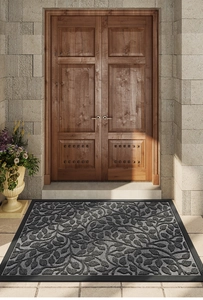 Macro shot of dark grey polypropylene doormat with leaf texture on stone floor entrance