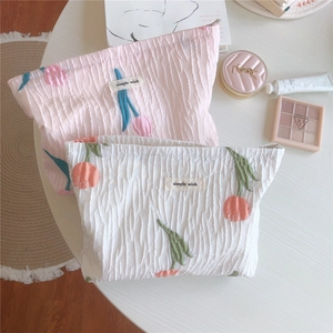 Détails de broderies tulipes sur pochettes en tissu rose et blanc au fini texturé gaufré