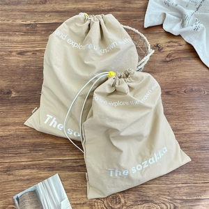 Detail of canvas drawstring bags with adjustable yellow toggles on a wooden floor