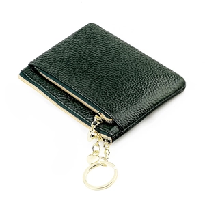 Detail of dark green pebble leather coin purse with gold zipper and heart keychain charm