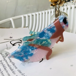Detail of a grasshopper-shaped acetate hair claw with blue and pink marble textures