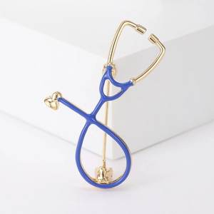Close-up of a gold stethoscope brooch with blue enamel detail on a white background