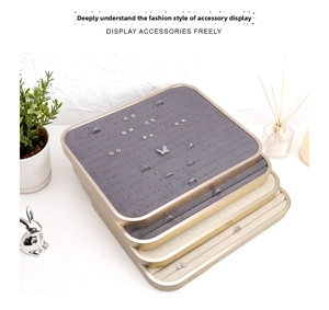Detail of stacked jewelry display trays with velvet ring slots and matte gold metal frames