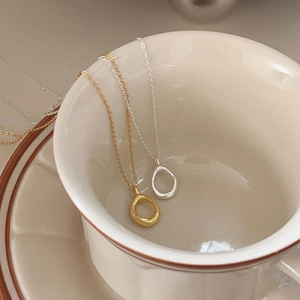 Detail of silver and gold teardrop necklaces on vintage ceramic showing irregular texture