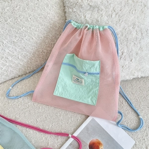 Detail of pink mesh backpack with green front pocket and blue drawstring shoulder straps